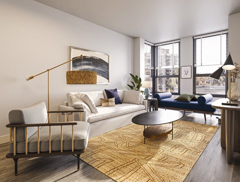 A living room with a white couch, blue couch, and a large painting on the wall.
