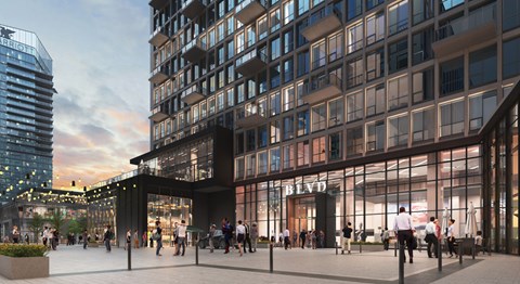 A modern building with a glass facade and a sign that reads "BLVD" is surrounded by people walking around.
