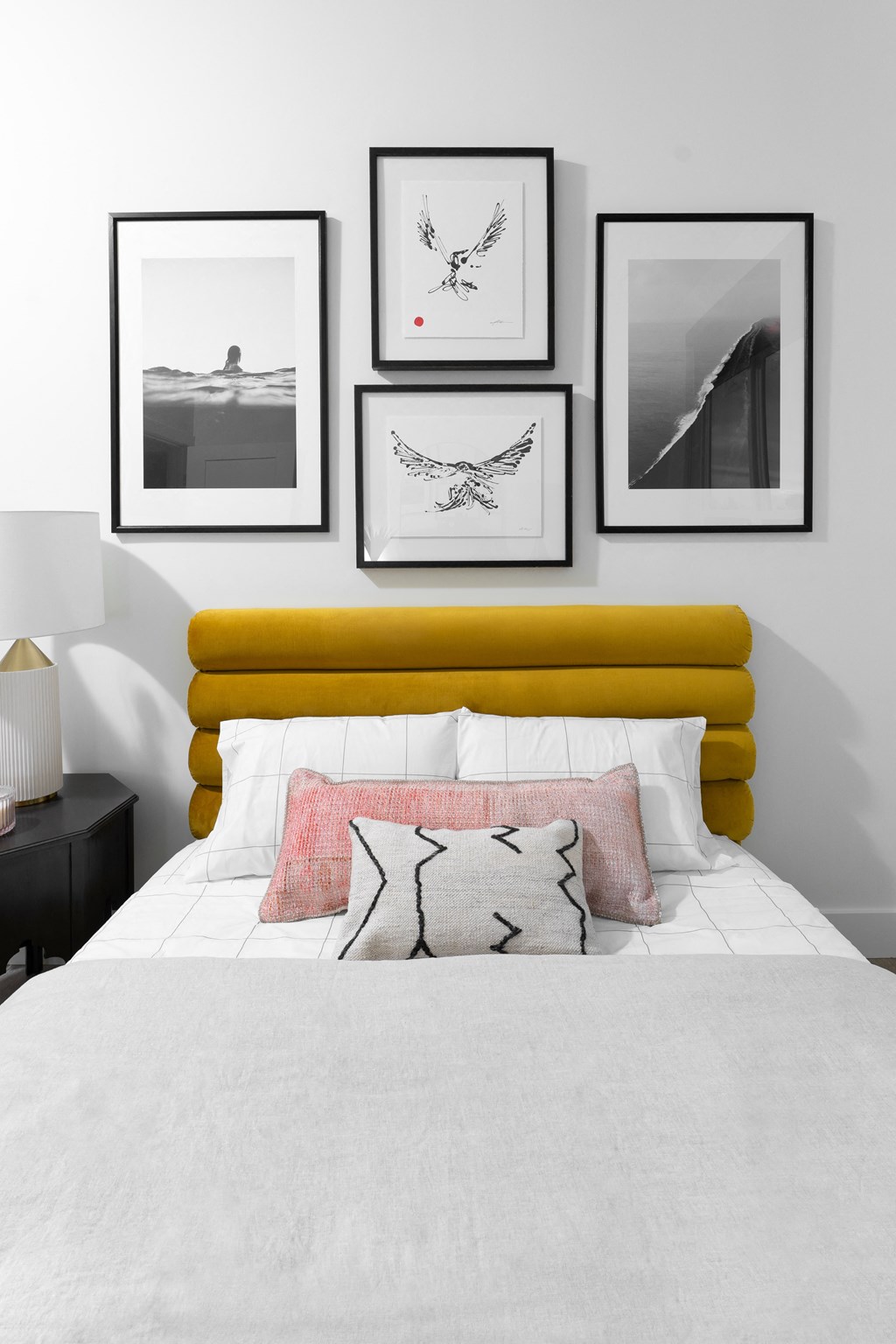 a bedroom with a white bed and pictures on the wall