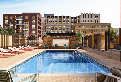 A pool surrounded by chairs and buildings in the background.