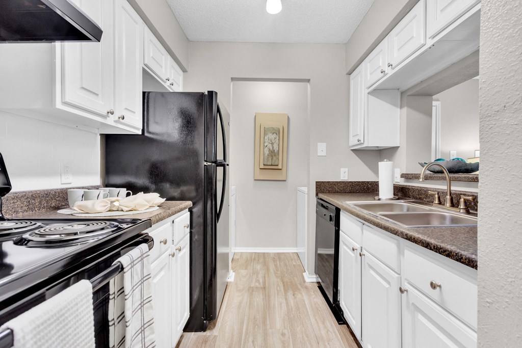 a kitchen with white cabinets and a black refrigerator