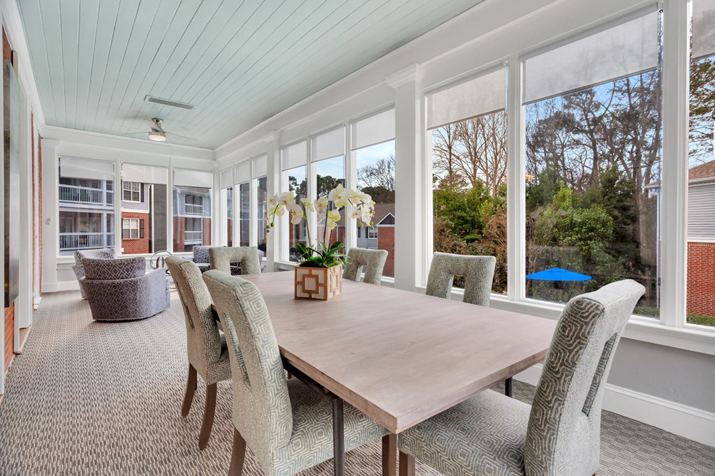 a dining room with a wooden table and chairs and large windows