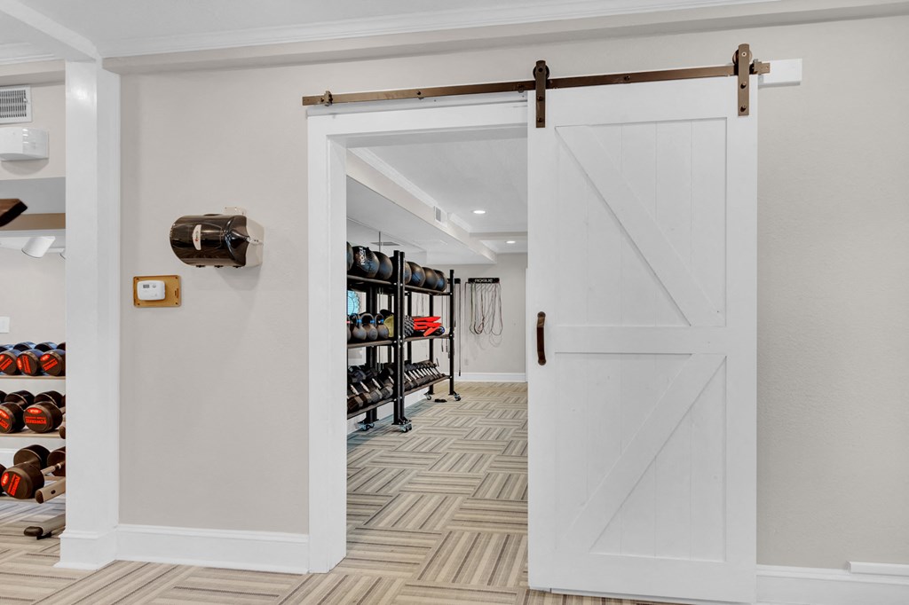 a white sliding barn door opens to a closet with shoe racks