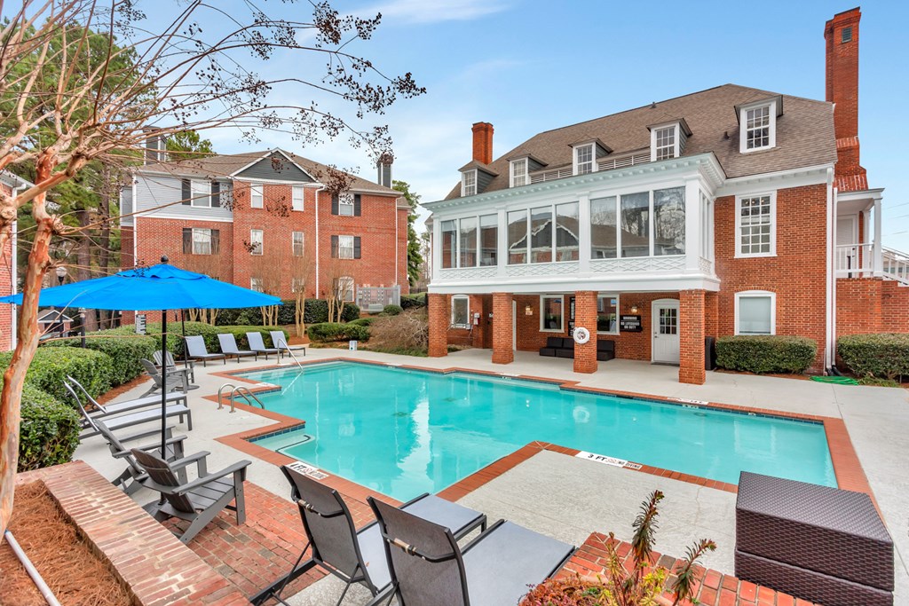 a swimming pool with chairs and a house in the background