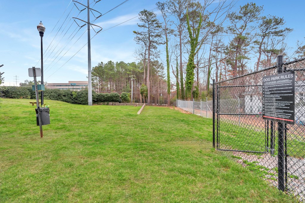 a fenced in area with a chain link fence and a sign in the grass