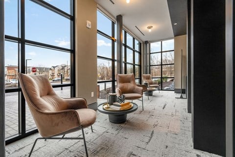 a lounge area with leather chairs and large windows