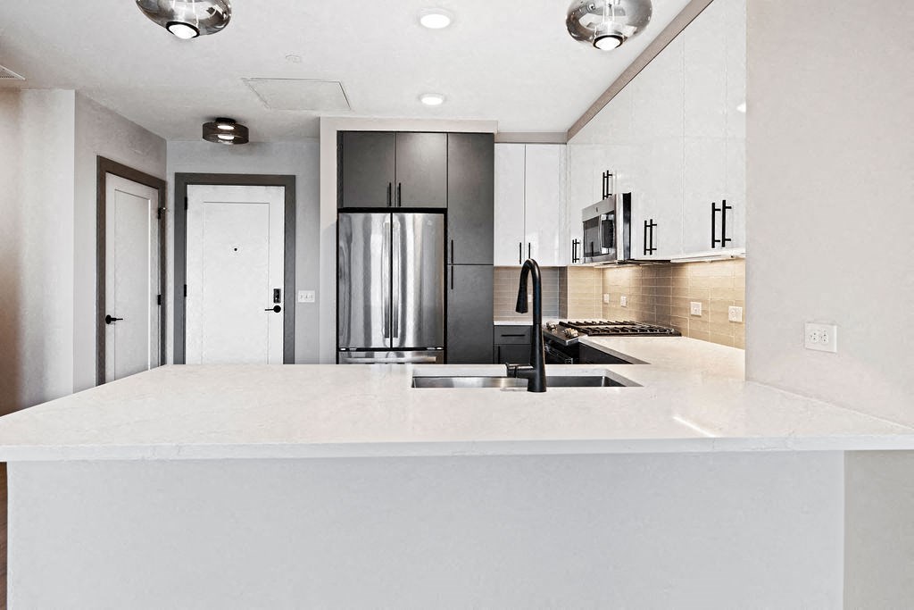 a white kitchen with a sink and a refrigerator at Madison West Elm, Conshohocken, PA
