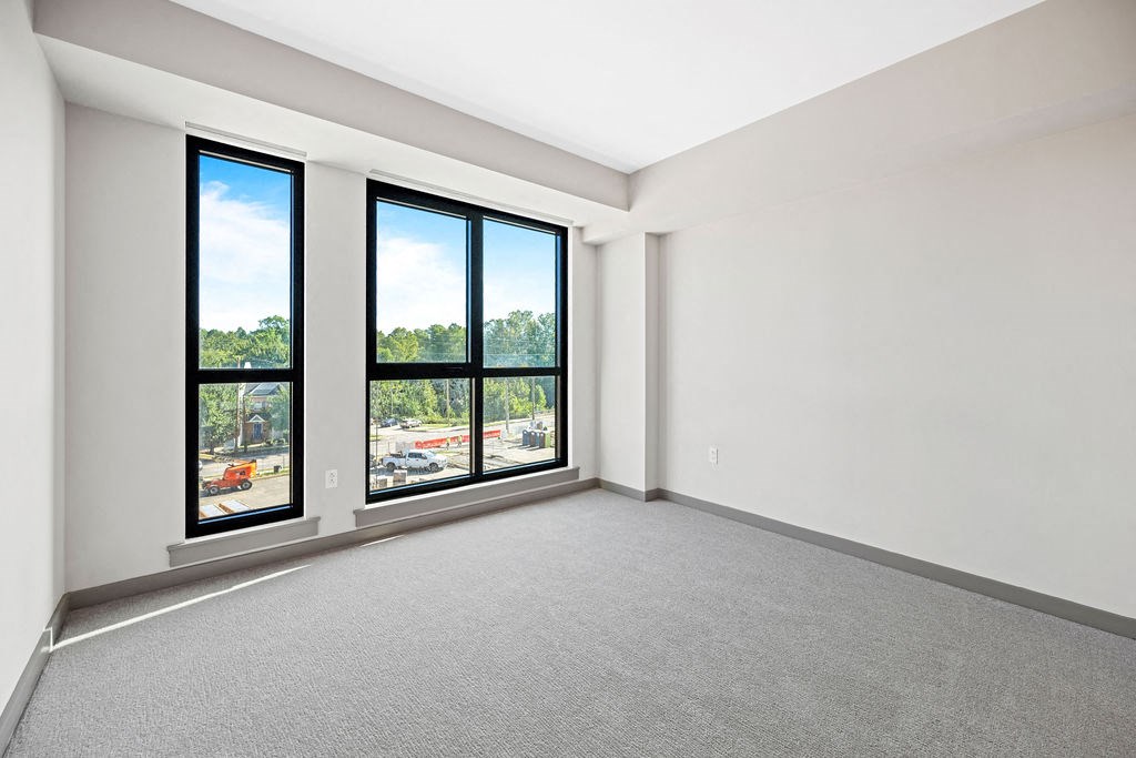 an empty living room with large windows and carpet at Madison West Elm, Conshohocken