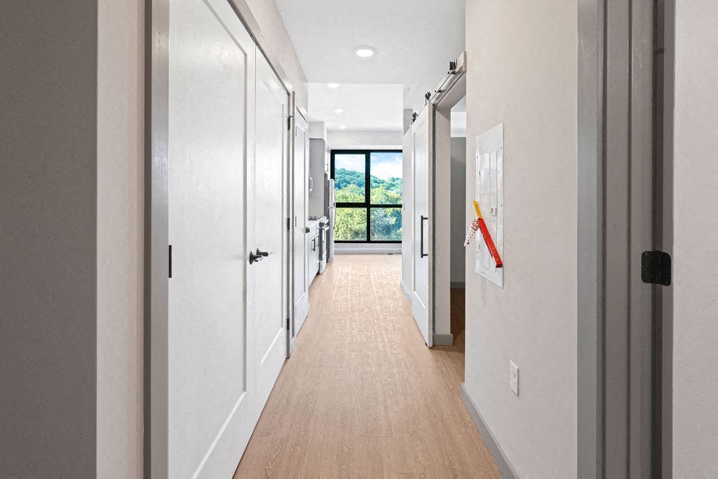 a long hallway with white walls and white doors and a window at Madison West Elm, Conshohocken, PA