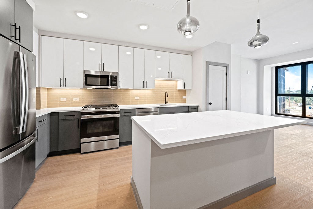 a white kitchen with a large island and stainless steel appliances at Madison West Elm, Conshohocken, 19428