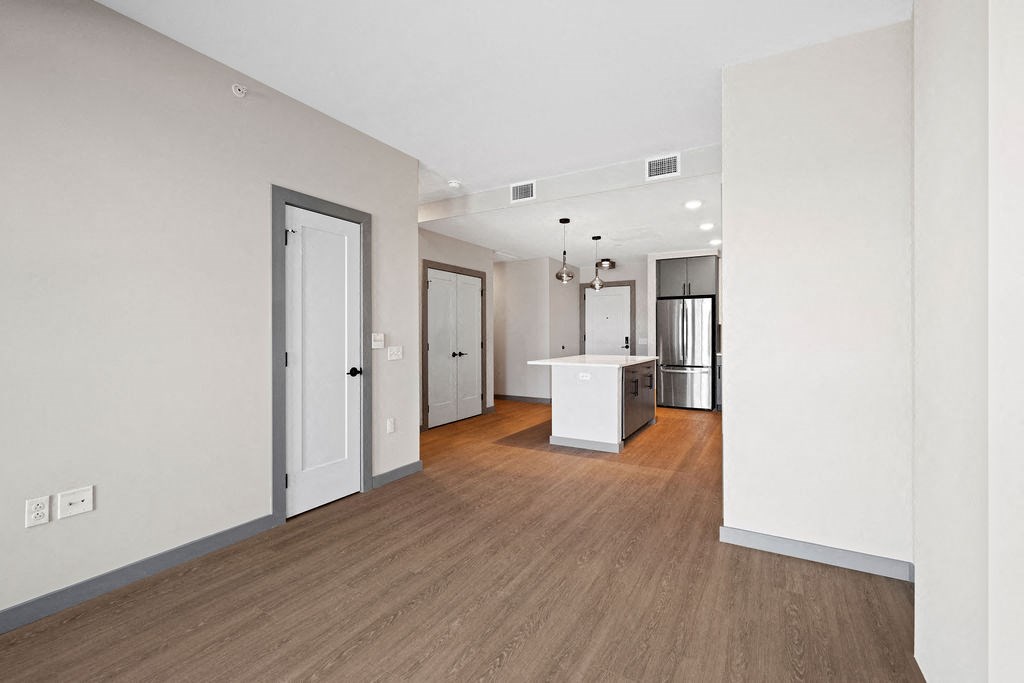 a renovated living room and kitchen with white walls and wood floors at Madison West Elm, Conshohocken