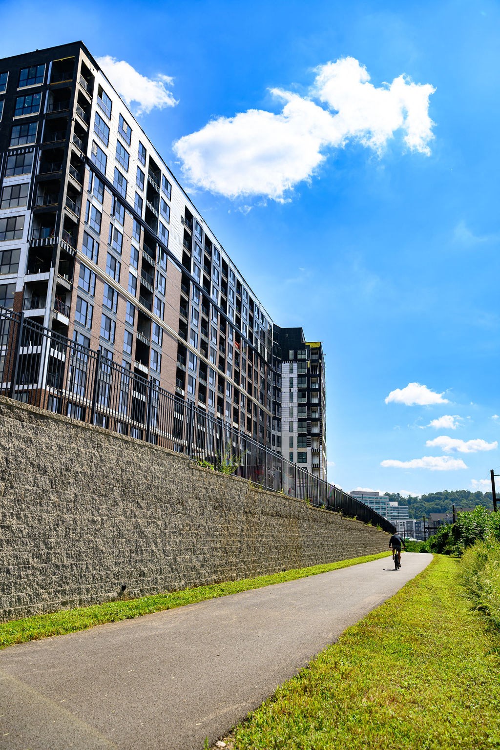 a person riding a bike down a path next to a building at Madison West Elm, Conshohocken