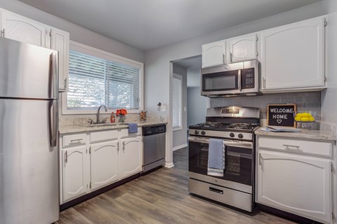 A kitchen with white cabinets and appliances, a refrigerator, a microwave, a stove, and a dishwasher.