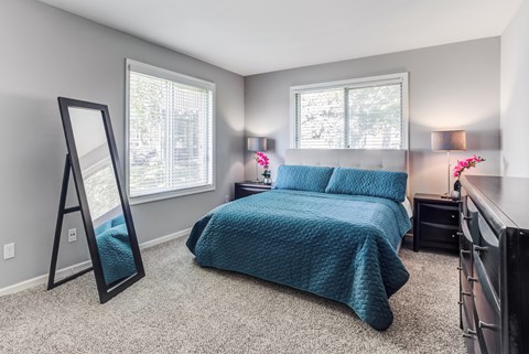 A bedroom with a bed, dresser, and mirror.