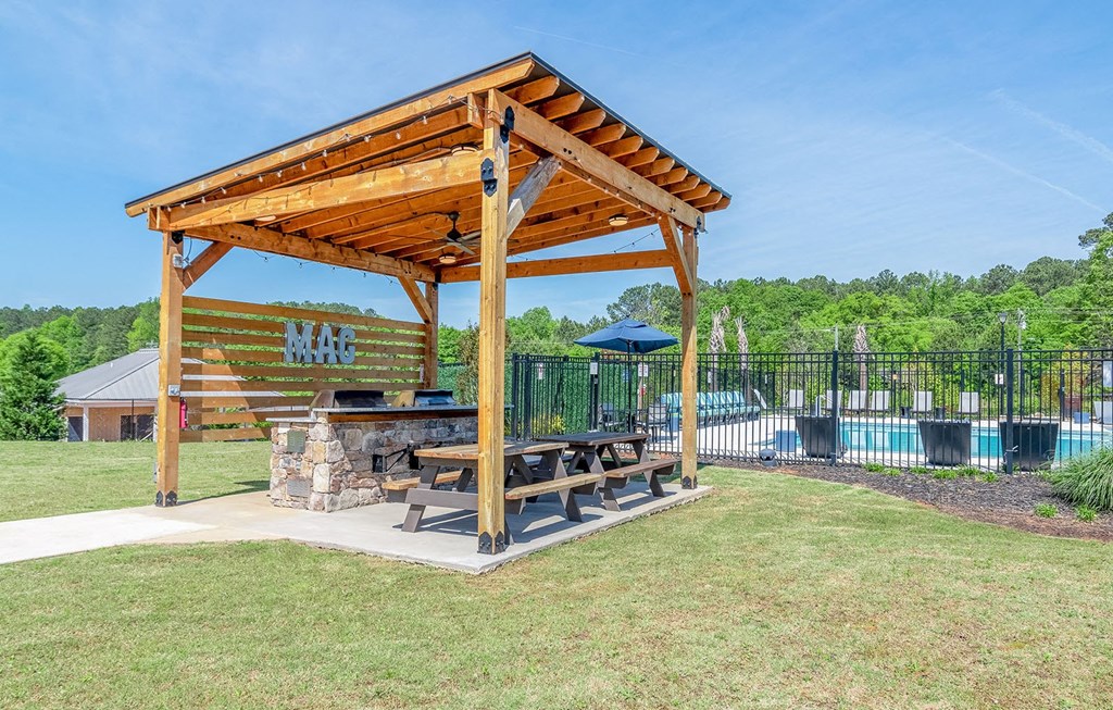 a picnic table under a wooden pavilion next to a swimming pool at Carmel Vista, McDonough, Georgia