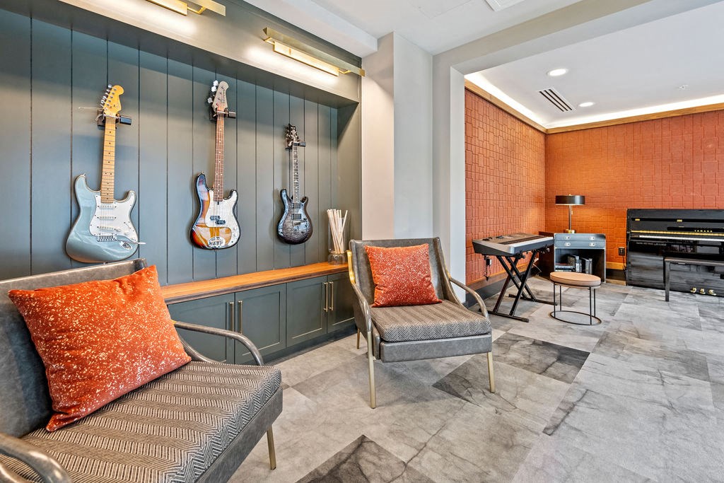 a room with guitars on the wall and chairs and a piano at The Harrison, Newtown Square, PA, 19073