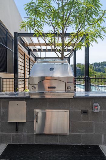 A BBQ grill is on a patio with a tree behind it at Madison West Elm, Conshohocken Pennsylvania