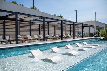 A pool with white loungers and a blue sky in the background at Madison West Elm, Conshohocken, PA