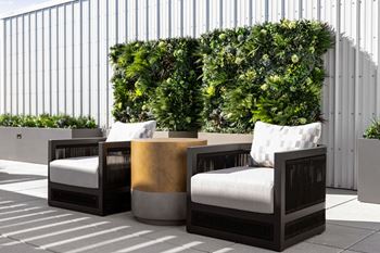 A set of three outdoor chairs with cushions and a small table with a gold-colored top at Madison West Elm, Conshohocken, 19428