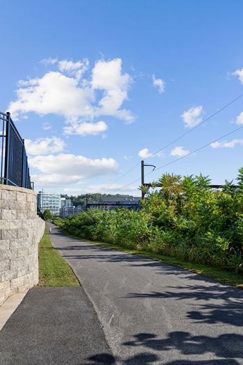 A paved path runs alongside a stone wall with a metal fence on top at Madison West Elm, Pennsylvania