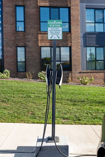 A charging station sign is on a pole in front of a building at Madison West Elm, Pennsylvania, 19428