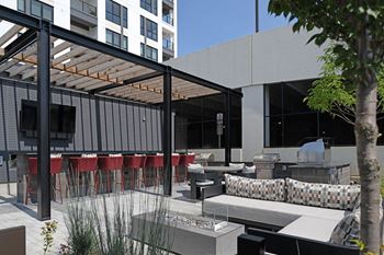 A modern outdoor seating area with red chairs and a glass table at Madison West Elm, Conshohocken