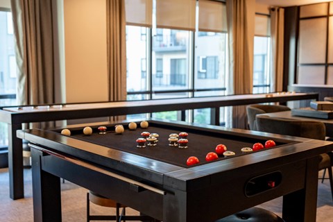 A game room with a shuffleboard table and couches at The Harrison.