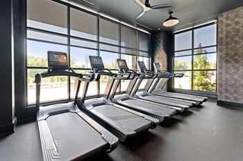 A row of treadmills in a gym with a fan on the ceiling at Madison West Elm, Pennsylvania