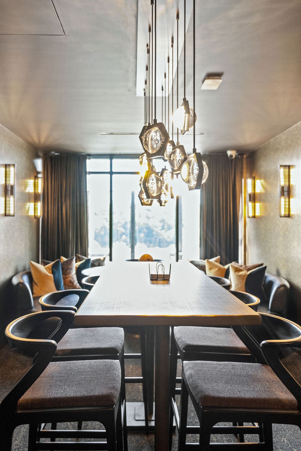 A long wooden table is surrounded by chairs in a room with a large window A long wooden table is surrounded by chairs in a room with a large window at Madison West Elm, Conshohocken
