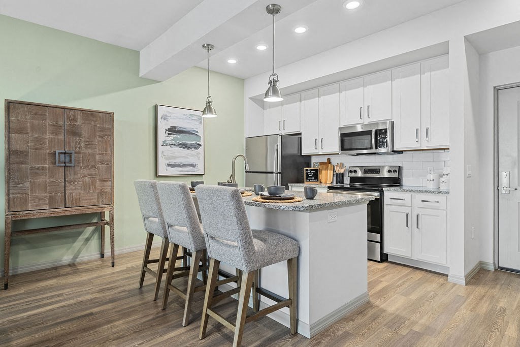 a kitchen with an island and three bar stools at Inspira, Naples, FL
