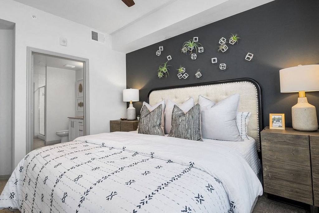 a bedroom with a bed and a grey wall and a bathroom at Inspira, Naples, Florida