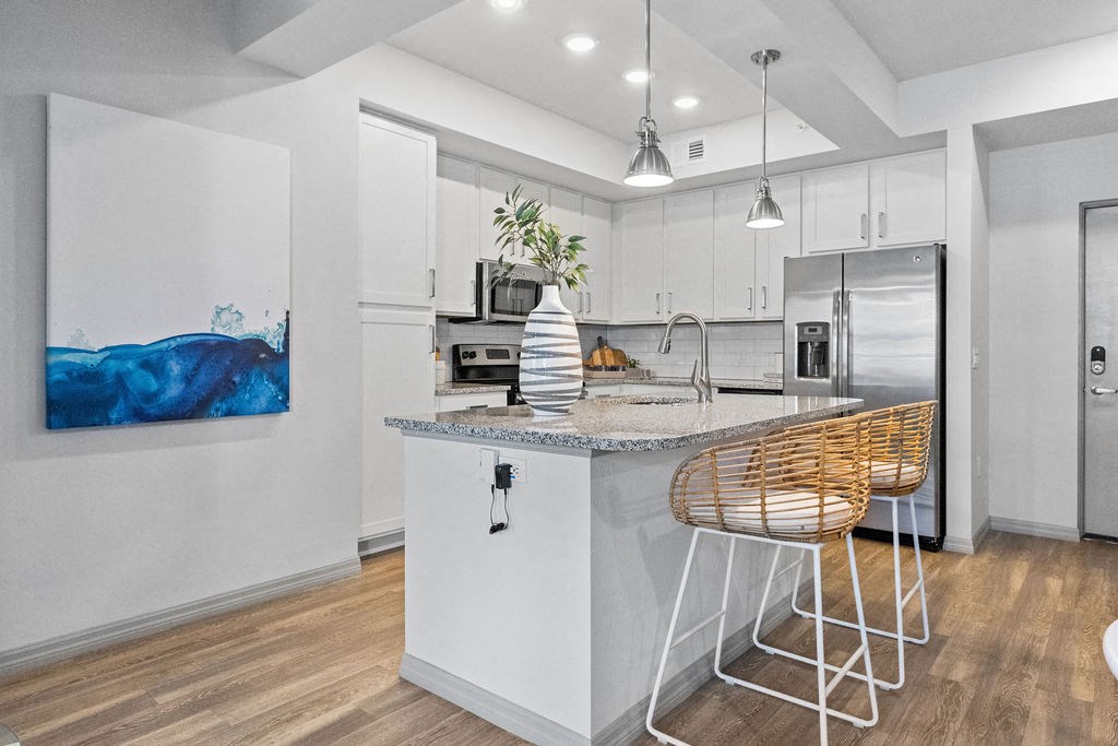 a kitchen with an island and a bar with stools at Inspira, Naples, FL, 34113