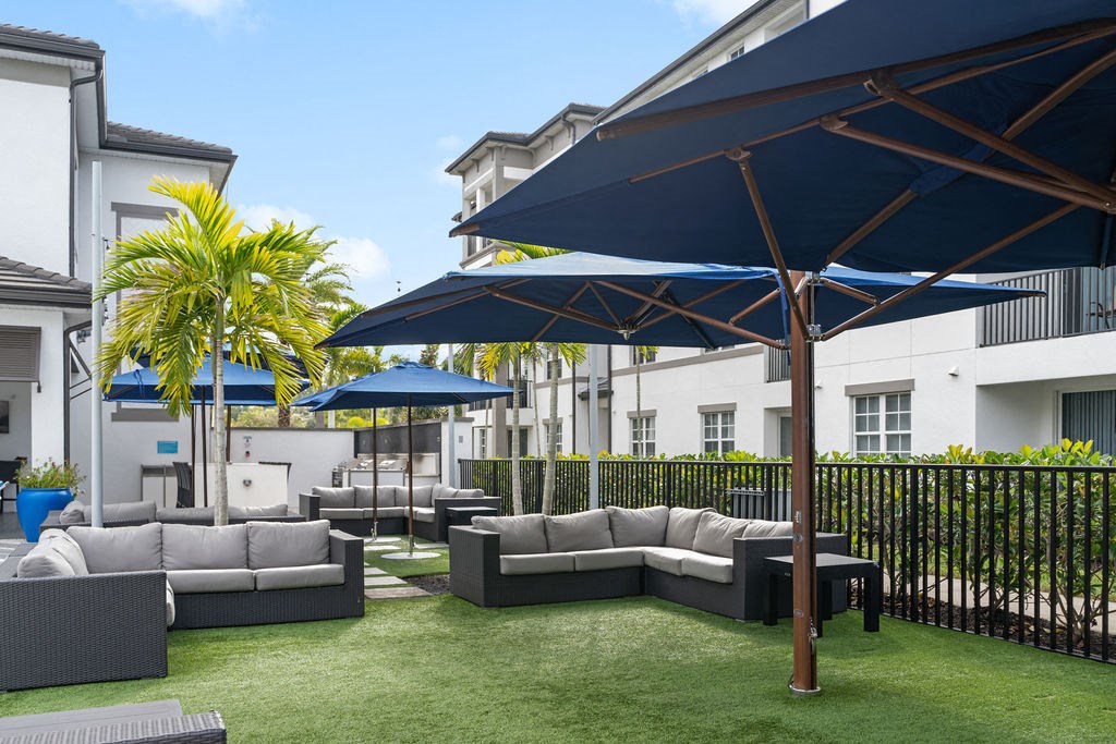 a lounge area with couches and umbrellas on a lawn at Inspira, Naples, FL, 34113