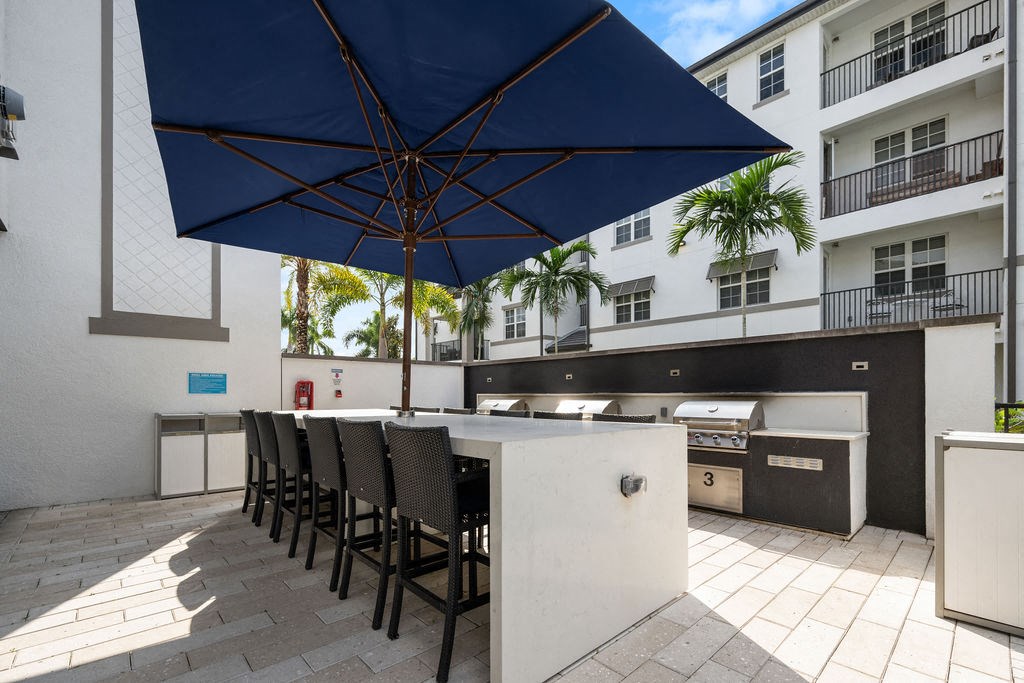 a kitchen with a bar and chairs under an umbrella at Inspira, Florida, 34113