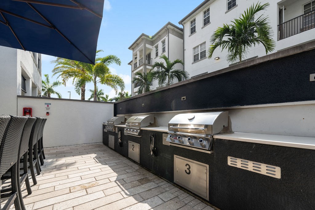 three barbecue grills on a patio in front of a building at Inspira, Naples, Florida