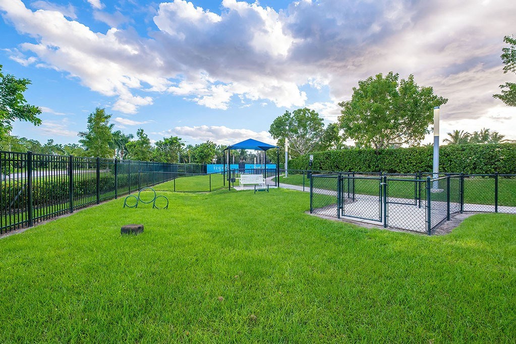 a fenced in dog park with a playground and a gazebo at Inspira, Naples, Florida