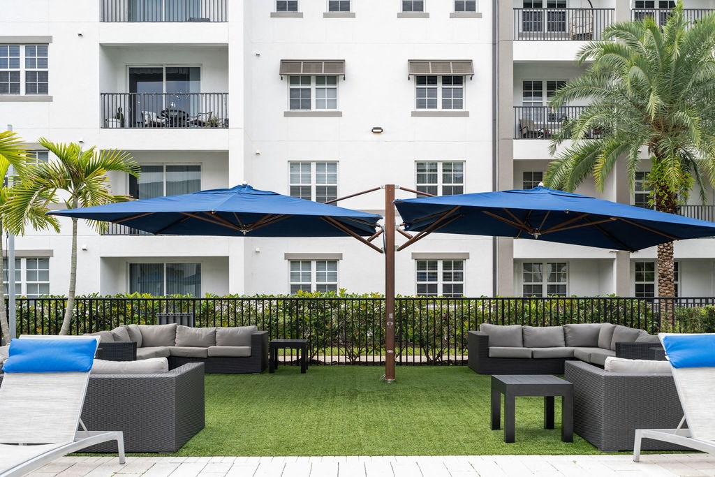 a patio with couches and umbrellas in front of a building at Inspira, Naples, FL, 34113
