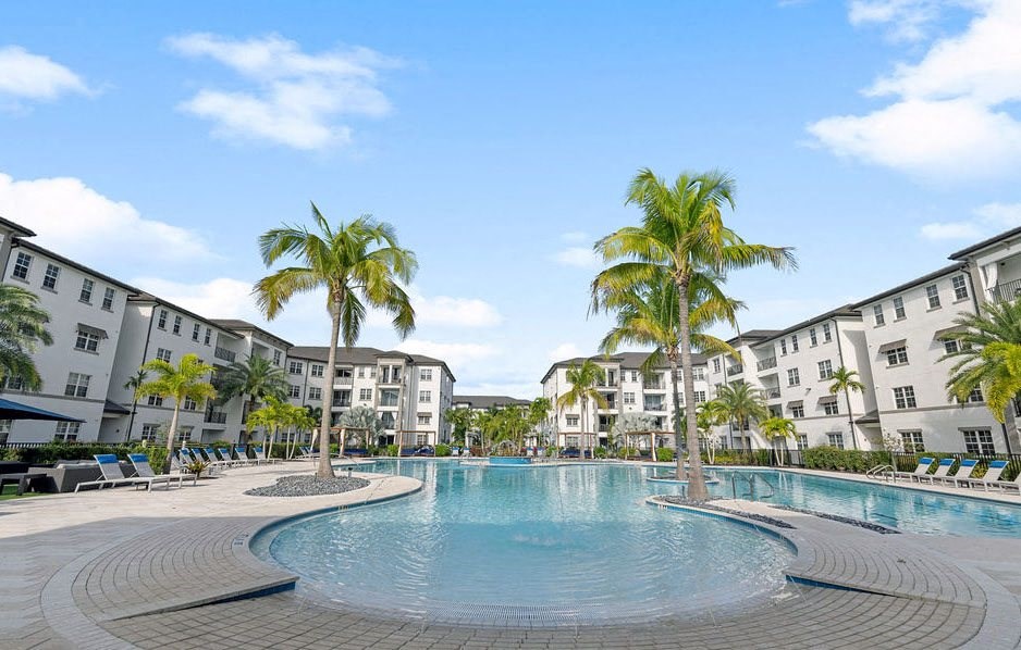 Palm trees flanking either side of the pool in the center of the apartment home buildings at Inspira, Naples, 34113