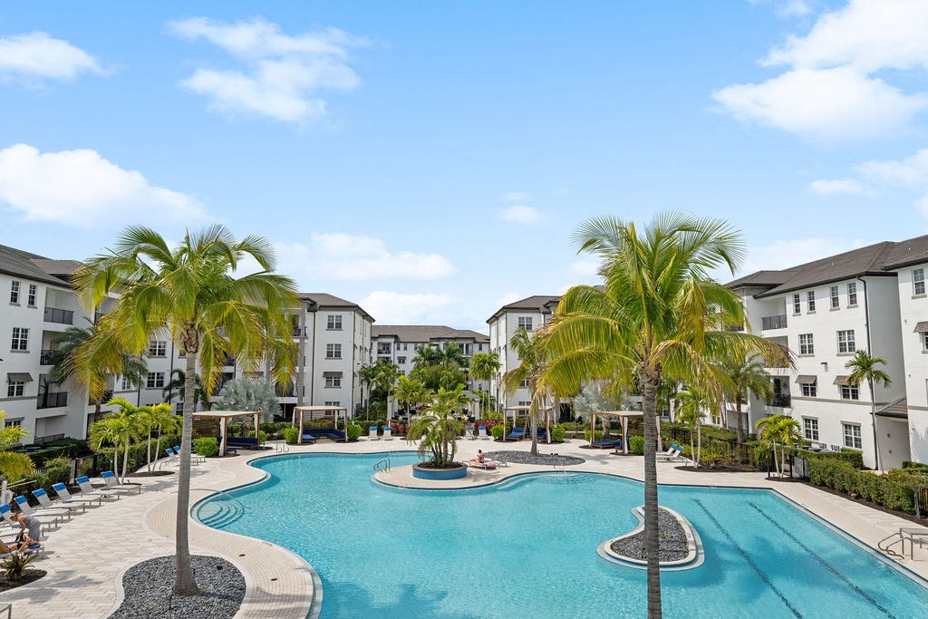 a large swimming pool with palm trees in front of some apartment buildings at Inspira, Naples, Florida