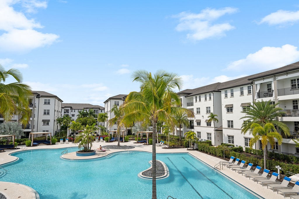 a large swimming pool with palm trees in front of apartment buildings at Inspira, Naples, 34113