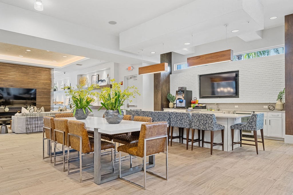 a dining area with a table and chairs and a kitchen with a television at Inspira, Naples, Florida