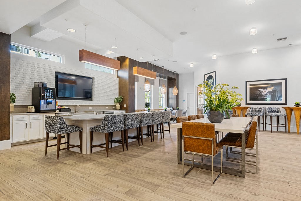 The clubhouse demonstration kitchen and large dining table flanked by bar height chairs with pub tables at Inspira, Naples, 34113