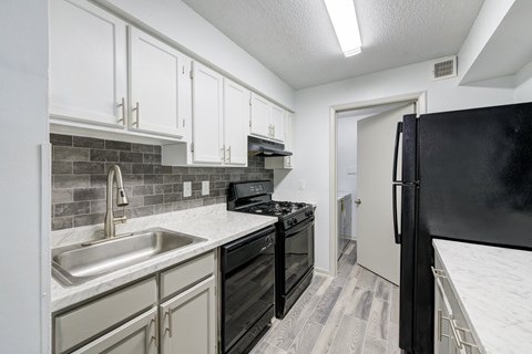 A kitchen with black appliances and white cabinets.