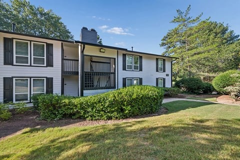 A white apartment building with a green lawn in front.