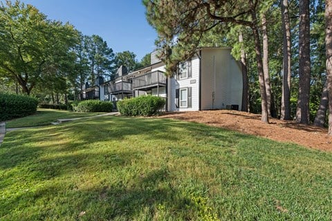 A house with a white exterior is surrounded by trees and grass.