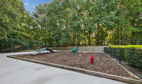 A playground with a red fire hydrant and a green slide.