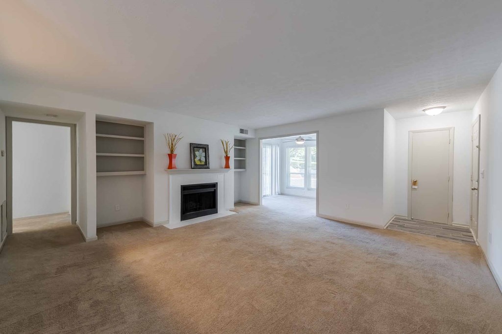 A spacious living room with a fireplace and a carpeted floor.