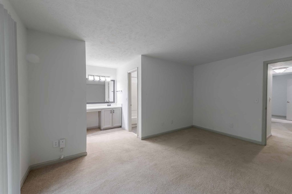 A spacious room with a window and a door leading to another room.