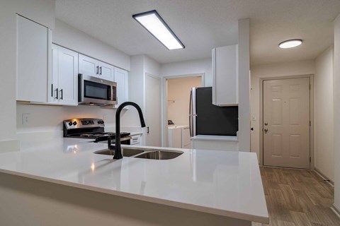 A kitchen with white cabinets and a black refrigerator.