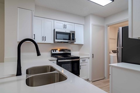A kitchen with white cabinets and a black refrigerator.